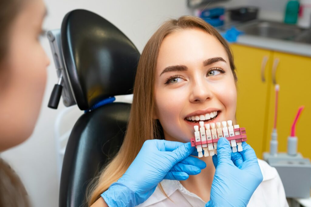 Dentist comparing tooth shades with a shade guide – DSA Dental Smile Art